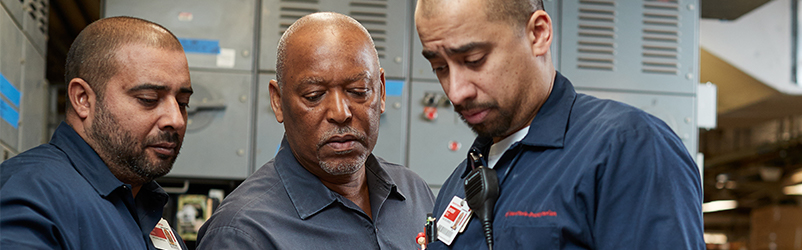 Three employees reviewing a clipboard